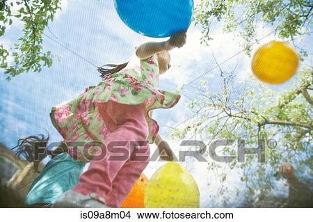 Young girls bouncing on garden trampoline with balloons View Large Photo Image Picture - Young girls bouncing on garden trampoline with balloons. Fotosearch