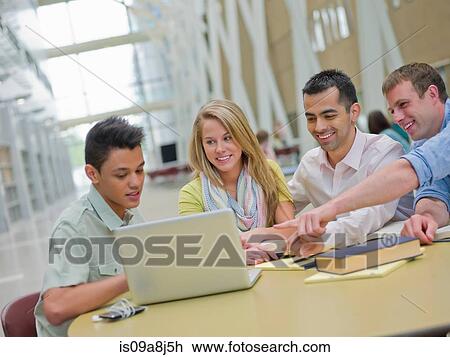 Stock Image - Young man and studying with tutors pointing at laptop. Fotosearch