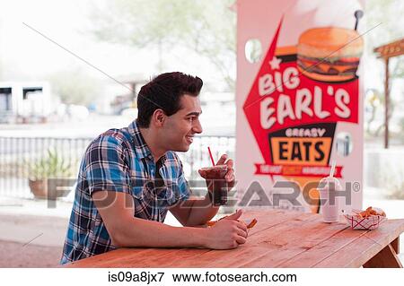 Young man drinking cola in diner, smiling View Large Photo Image Stock Photo - Young man drinking cola in diner, smiling. Fotosearch