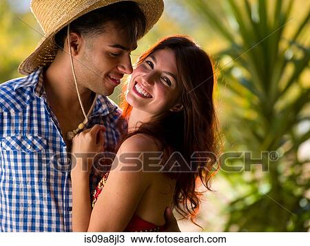 Stock Image - Young man embracing smiling woman, portrait. Fotosearch
