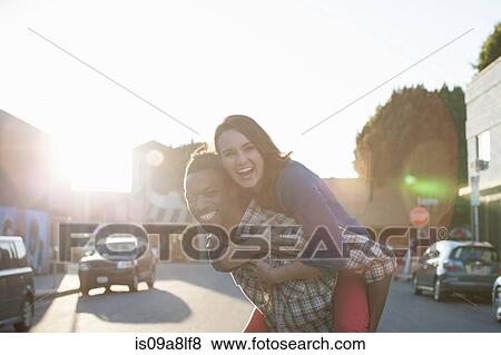 Stock Photo - Young man giving woman piggy back. Fotosearch