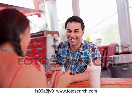 Young man laughing in diner as girlfriend uses mobile phone View Large Photo Image Stock Image - Young man laughing in diner as girlfriend uses mobile phone. Fotosearch