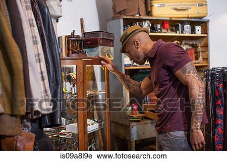 Young man looking into cabinet in vintage shop View Large Photo Image Stock Image - Young man looking into cabinet in vintage shop. Fotosearch