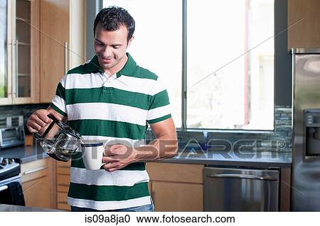 Young man pouring coffee from pot in kitchen, smiling View Large Photo Image Stock Image - Young man pouring coffee from pot in kitchen, smiling. Fotosearch