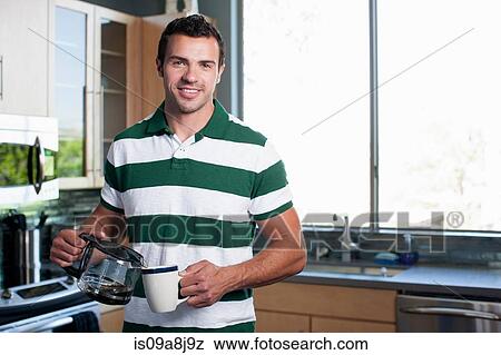 Young man pouring coffee from pot in kitchen, portrait View Large Photo Image Stock Photo - Young man pouring coffee from pot in kitchen, portrait. Fotosearch