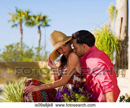 Stock Photo - Young man sitting and kissing woman's shoulder. Fotosearch