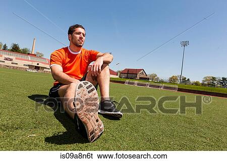 Stock Photograph - Young man taking a break on sport stadium grass. Fotosearch