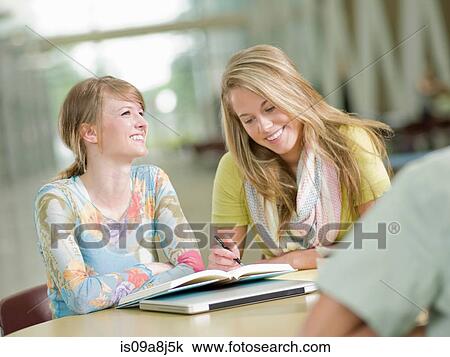 Young tutor writing in student's book, smiling View Large Photo Image Stock Image - Young tutor writing in student's book, smiling. Fotosearch
