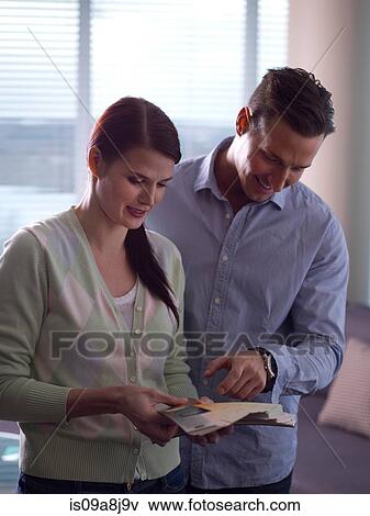 Stock Photo - Young woman and mid adult man looking at colour swatches. Fotosearch