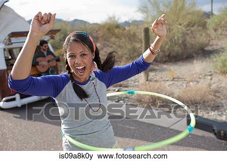 Stock Photo - Young woman dancing with plastic hoop on road, portrait. Fotosearch