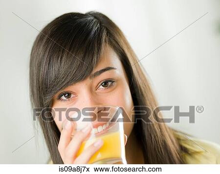 Stock Photo - Young woman drinking orange juice, portrait. Fotosearch
