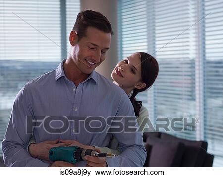 Young woman embracing mid adult man holding hand drill View Large Photo Image Stock Photo - Young woman embracing mid adult man holding hand drill. Fotosearch
