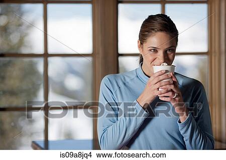 Young woman enjoying hot drink indoors View Large Photo Image Picture - Young woman enjoying hot drink indoors. Fotosearch