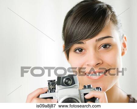 Stock Photo - Young woman holding camera, portrait. Fotosearch
