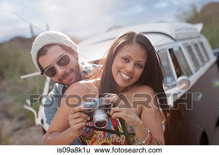 Young woman holding camera with boyfriend on road trip, smiling View Large Photo Image Stock Photograph - Young woman holding camera with boyfriend on road trip, smiling. Fotosearch