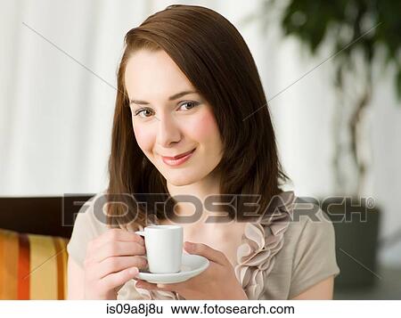 Stock Photograph - Young woman holding coffee cup, portrait. Fotosearch