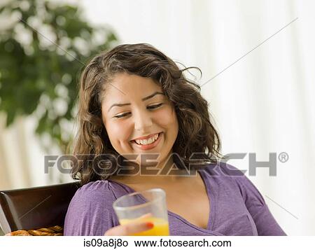 Young woman holding glass of orange juice, smiling View Large Photo Image Picture - Young woman holding glass of orange juice, smiling. Fotosearch