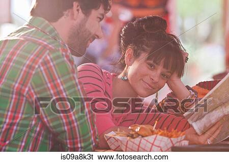 Stock Photograph - Young woman holding map with man in sunlit diner. Fotosearch