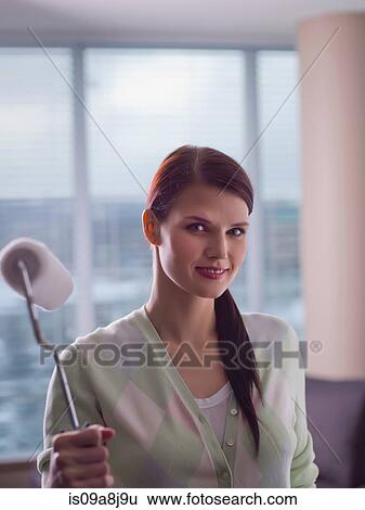 Young woman holding paint roller, portrait View Large Photo Image Stock Photograph - Young woman holding paint roller, portrait. Fotosearch