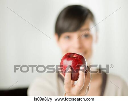 Stock Photo - Young woman holding red apple, close up. Fotosearch