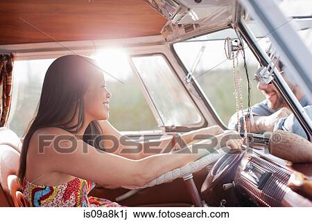 Stock Image - Young woman in camper van and smiling at boyfriend. Fotosearch
