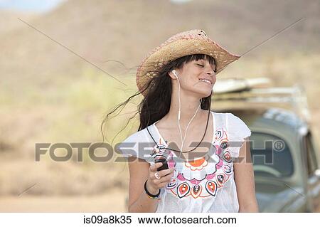 Young woman in cowboy hat wearing earphones, smiling View Large Photo Image Stock Photography - Young woman in cowboy hat wearing earphones, smiling. Fotosearch