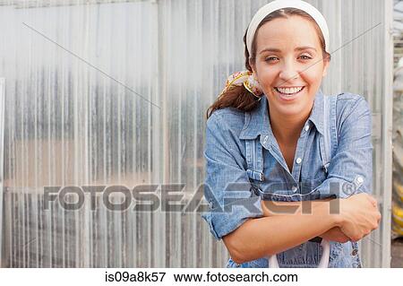 Young woman in dungarees leaning on spade in garden centre, portrait View Large Photo Image Stock Photo - Young woman in dungarees leaning on spade in garden centre, portrait. Fotosearch