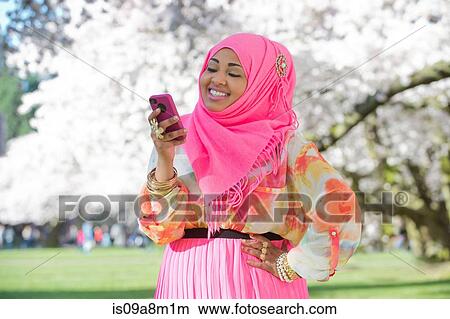 Young woman in park wearing pink headscarf and skirt View Large Photo Image Picture - Young woman in park wearing pink headscarf and skirt. Fotosearch