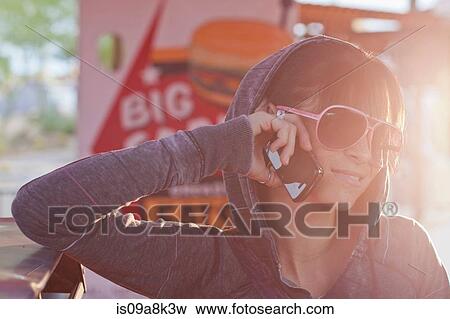 Young woman in sunglasses using mobile phone in sunlit diner View Large Photo Image Stock Photo - Young woman in sunglasses using mobile phone in sunlit diner. Fotosearch