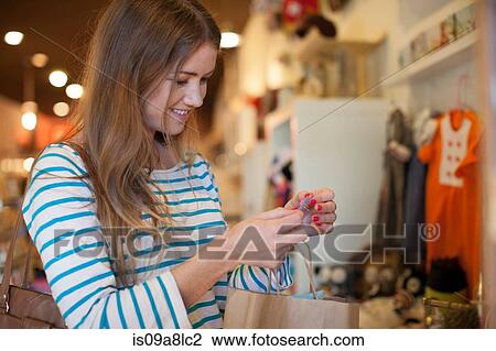 Stock Image - Young woman in vintage shop with paper shopping bag. Fotosearch