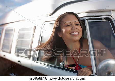 Young woman leaning out of the window of camper van, smiling View Large Photo Image Stock Photo - Young woman leaning out of the window of camper van, smiling. Fotosearch