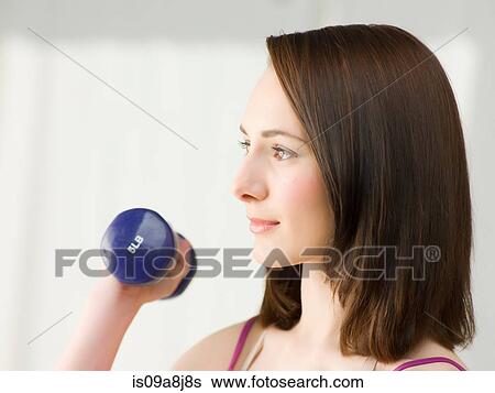 Stock Photograph - Young woman lifting dumb bells, close up. Fotosearch