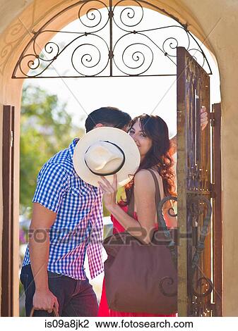 Stock Image - Young woman looking over sun hat by iron gate, portrait. Fotosearch
