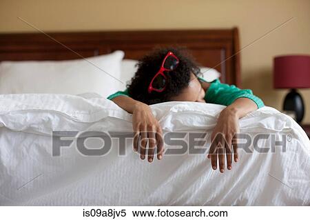 Stock Photography - Young woman lying on bed, close up. Fotosearch