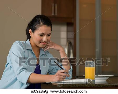 Young woman reading newspaper over orange juice View Large Photo Image Stock Image - Young woman reading newspaper over orange juice. Fotosearch