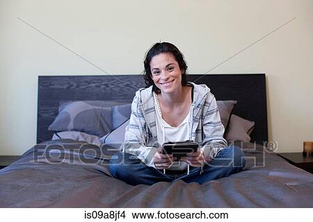 Picture - Young woman sitting bed with electronic book, portrait. Fotosearch