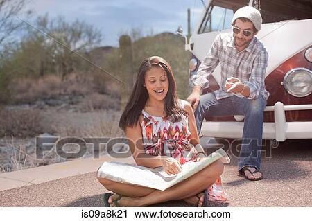 Young woman sitting in road reading map on road trip, smiling View Large Photo Image Stock Image - Young woman sitting in road reading map on road trip, smiling. Fotosearch