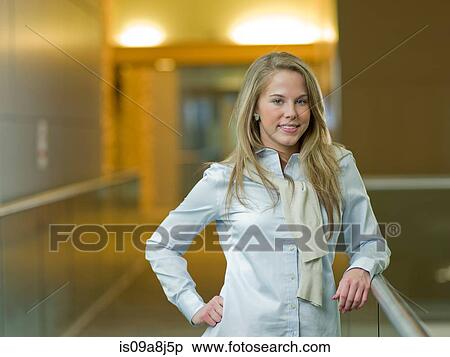 Stock Photography - Young woman smiling in corridor, portrait. Fotosearch