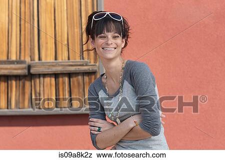 Young woman smiling with arms folded, portrait View Large Photo Image Stock Photo - Young woman smiling with arms folded, portrait. Fotosearch