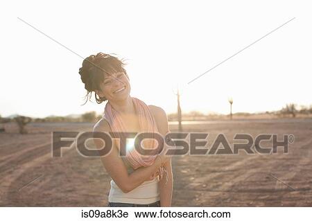 Stock Image - Young woman standing in desert, portrait. Fotosearch