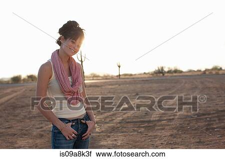 Stock Image - Young woman standing in desert, portrait. Fotosearch