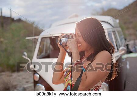Young woman taking photograph on road trip, smiling View Large Photo Image Stock Photo - Young woman taking photograph on road trip, smiling. Fotosearch