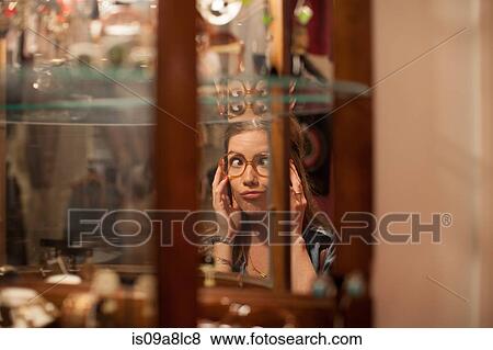 Young woman trying on glasses and pulling faces in vintage shop View Large Photo Image Stock Photo - Young woman trying on glasses and pulling faces in vintage shop. Fotosearch