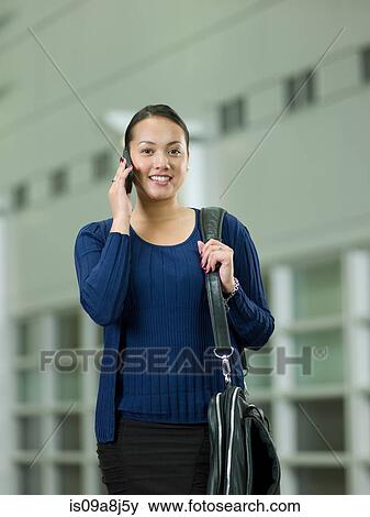 Stock Photo - Young woman using cellphone, smiling. Fotosearch