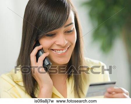 Young woman using credit card over the phone View Large Photo Image Stock Photo - Young woman using credit card over the phone. Fotosearch