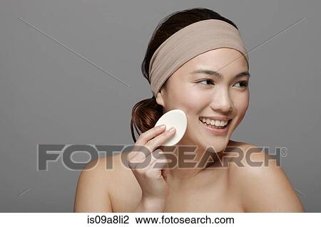 Stock Image - Young woman using make up sponge. Fotosearch