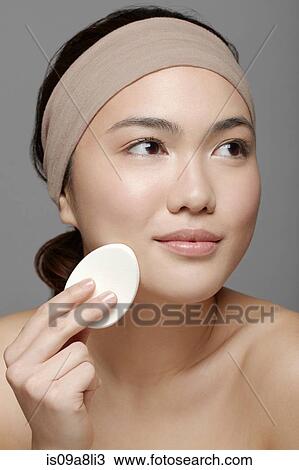 Stock Image - Young woman using make up sponge. Fotosearch
