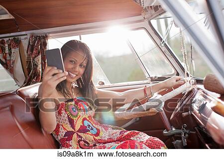 Young woman using mobile phone in camper van, smiling View Large Photo Image Picture - Young woman using mobile phone in camper van, smiling. Fotosearch