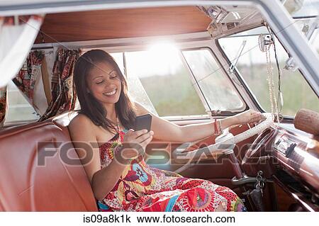 Stock Image - Young woman using mobile phone in camper van. Fotosearch