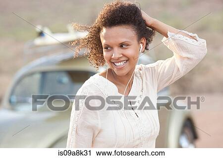 Young woman wearing earphones in desert on road trip, smiling View Large Photo Image Stock Image - Young woman wearing earphones in desert on road trip, smiling. Fotosearch